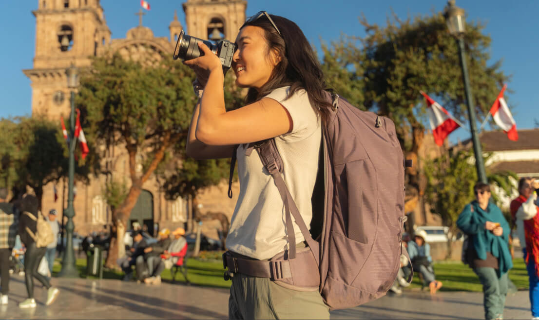 Traveler using Osprey Fairview travel backpack exploring vibrant city streets
