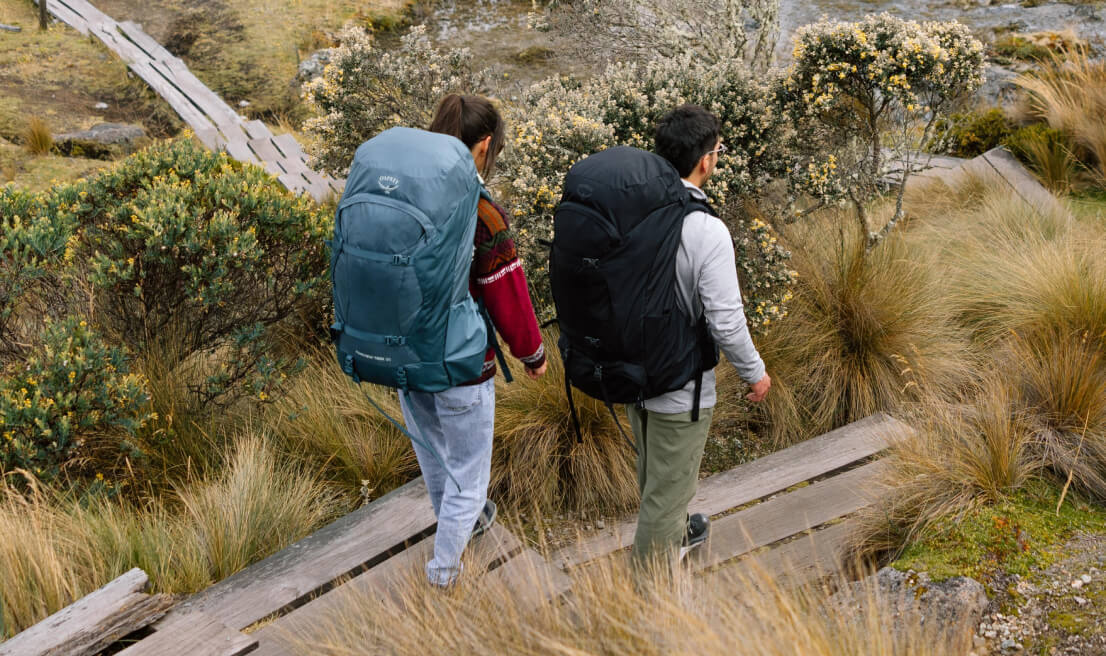 Backpackers with Osprey Farpoint and Fairview Trek backpacks on hillside trail