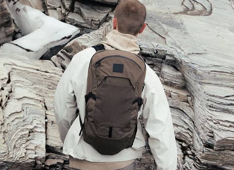 Rear view of a person wearing an Osprey backpack in an outdoor industrial setting.