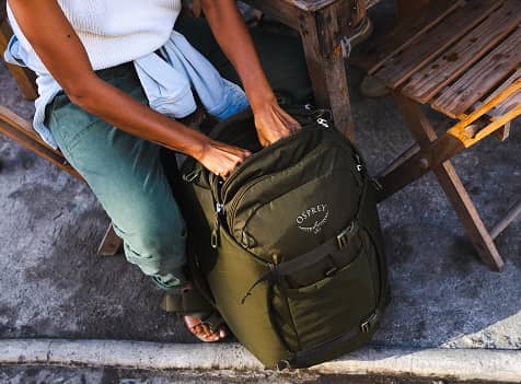 Top-down view of an Osprey travel backpack being packed outdoors.