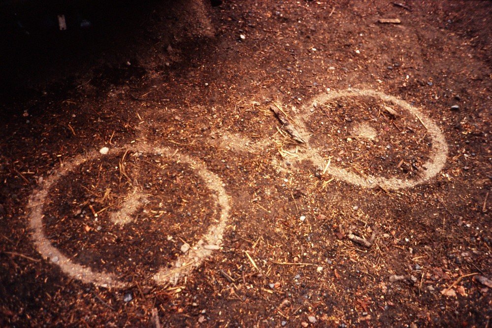 An outline of a bike in the dirt.