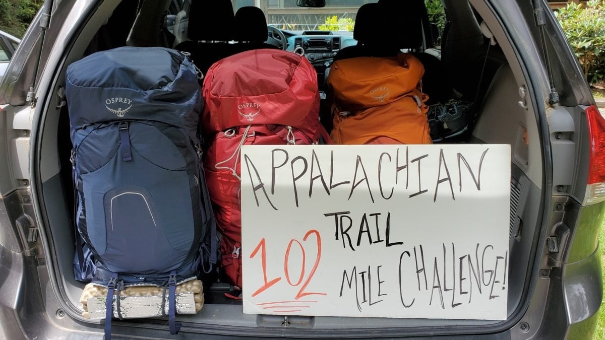 Three Osprey packs in a trunk with a sign that says 
