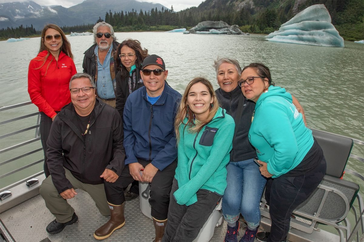 A group of people on a boat with a river landscape behind them