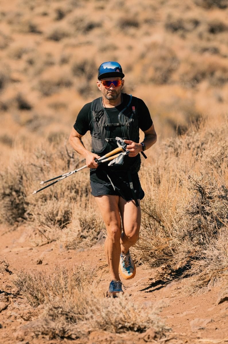 A man wearing running gear and holding trekking poles jogging through Death Valley National Monument