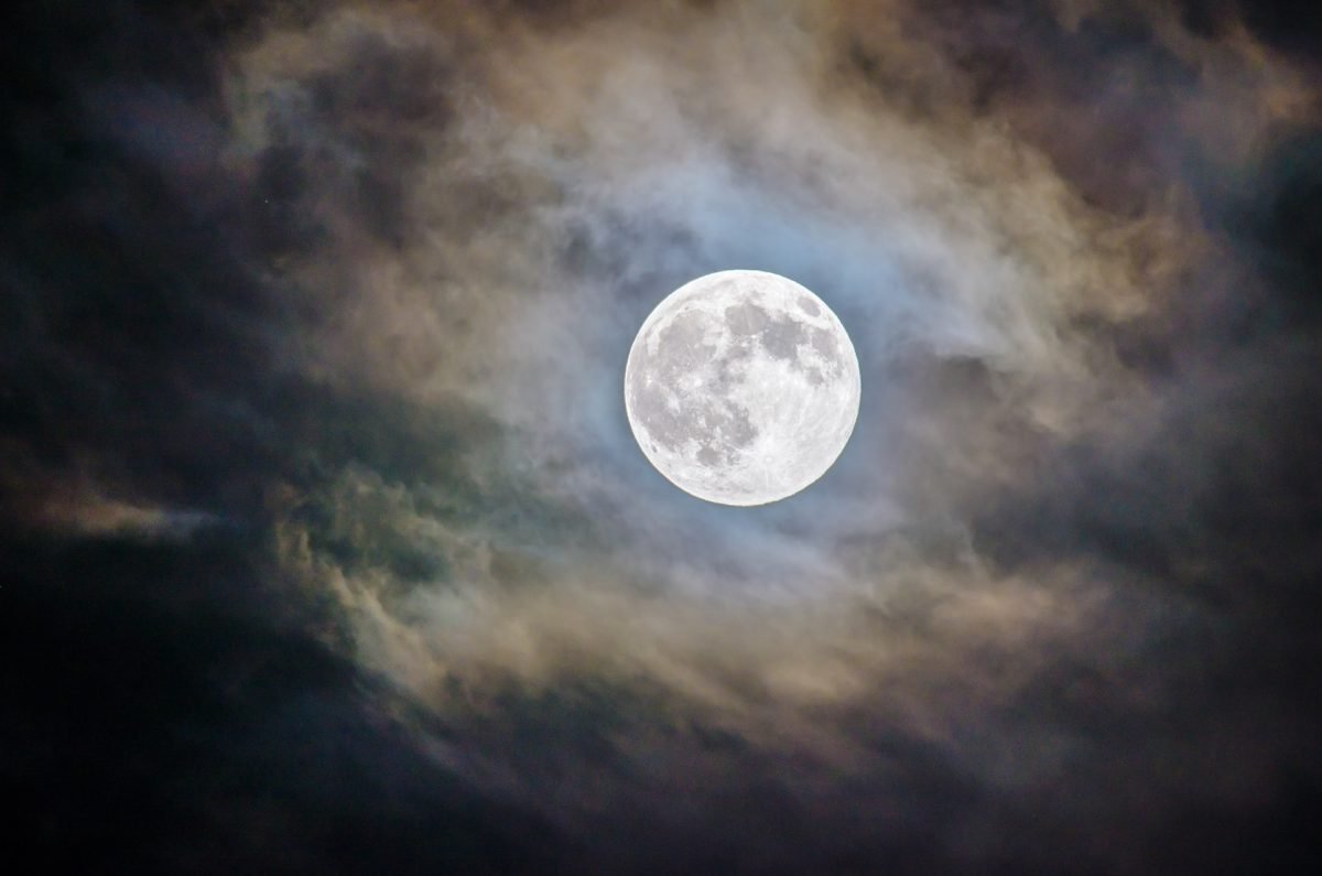 A full moon surrounded by wispy coulds
