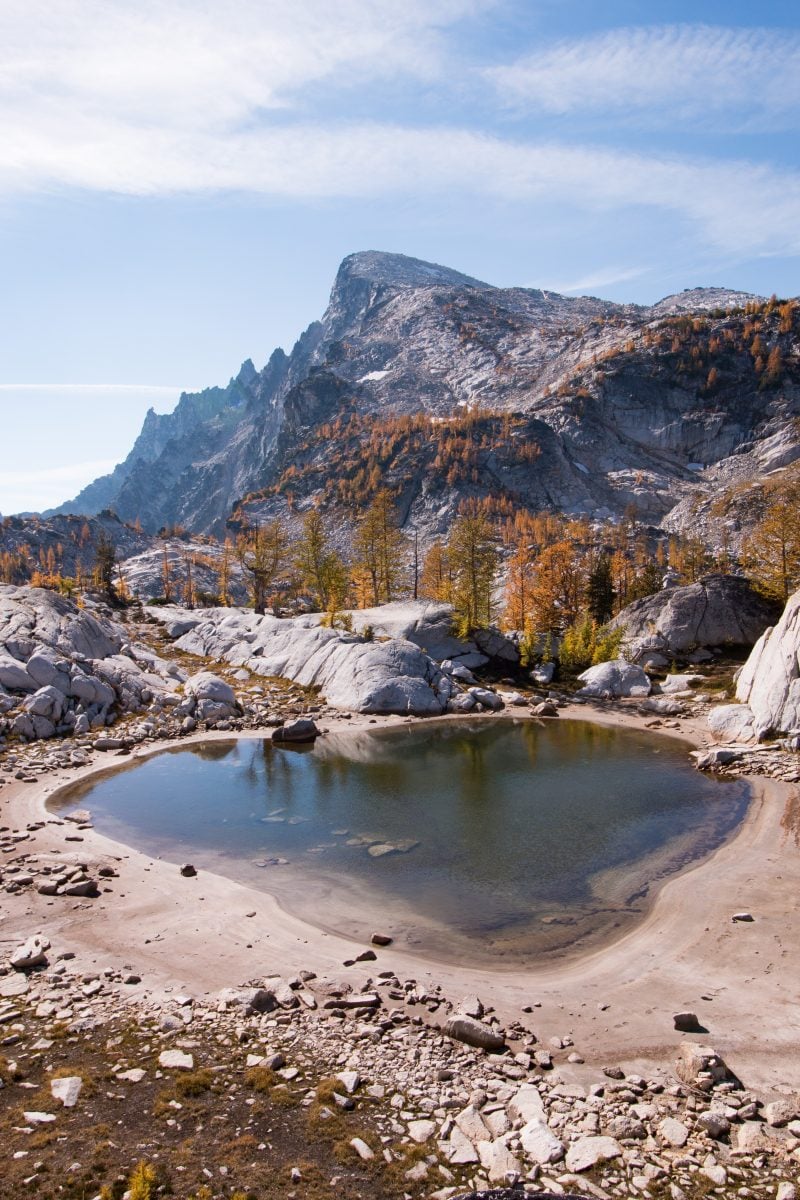 A landscape view of a small pond with a mountain range in the background
