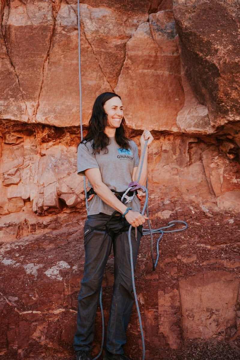 A woman geared up in climbing equipment providing a demonstration 
