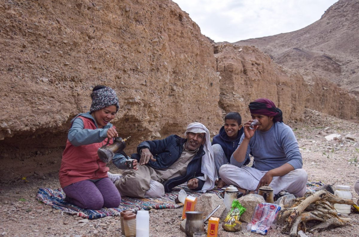 A group of people gathered sharing snacks and tea on a break from trekking along the Sinai Trail