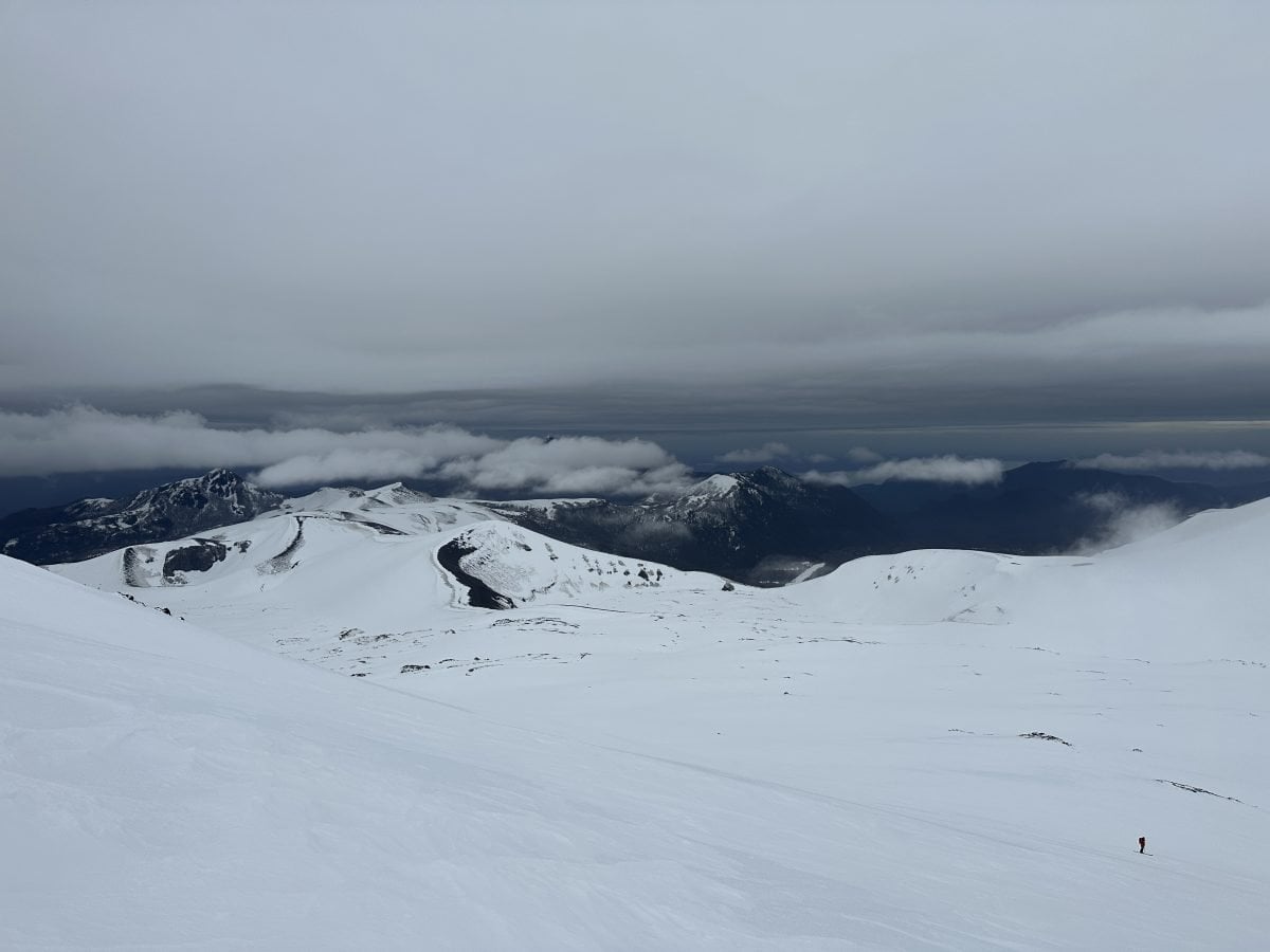 A landscape view of a snowy mountain and a storm up above