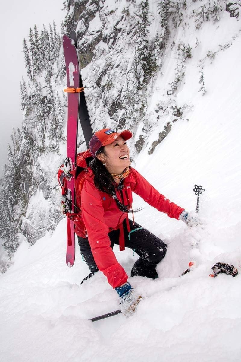A woman smiling and touring up a snowy mountain in ski gear