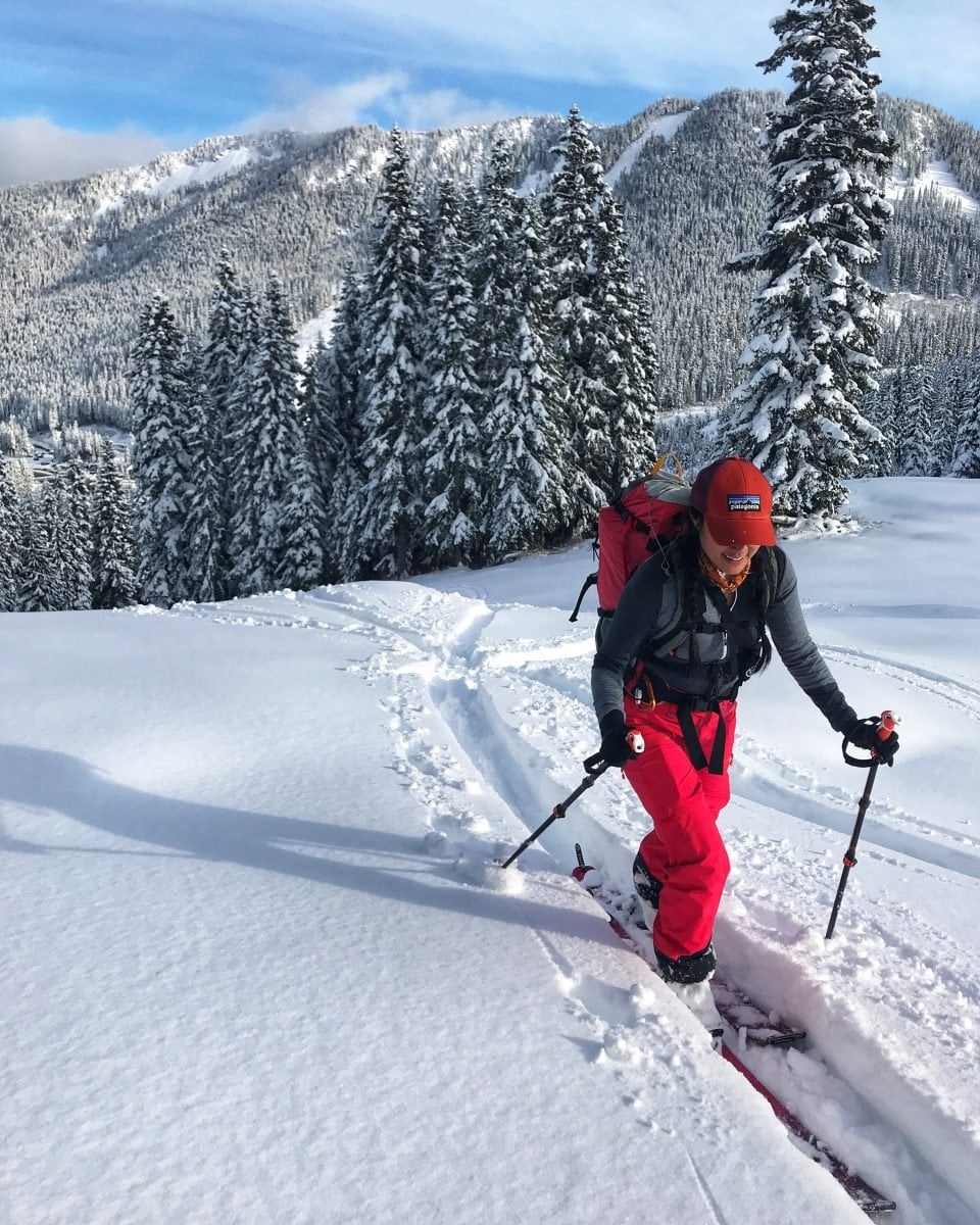 A woman touring on skis up a mountain