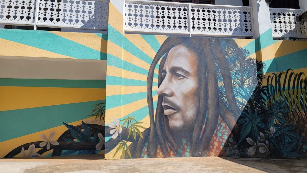 A mural of Bob Marley with a yellow and turquoise background