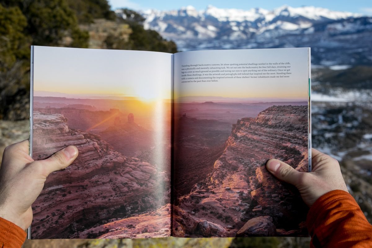 A person wearing an orange shirt holding a magazine open to a feature image with text in the top right corner