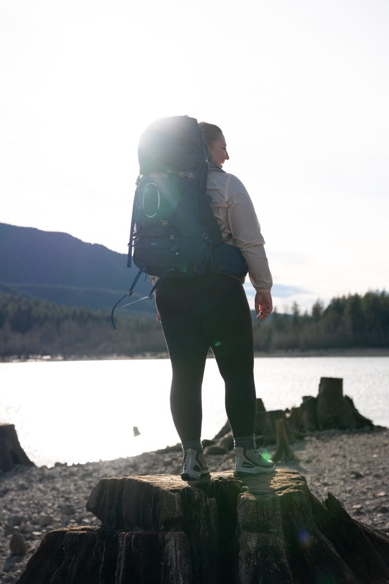 A woman standing near a lake in her backpacking gear
