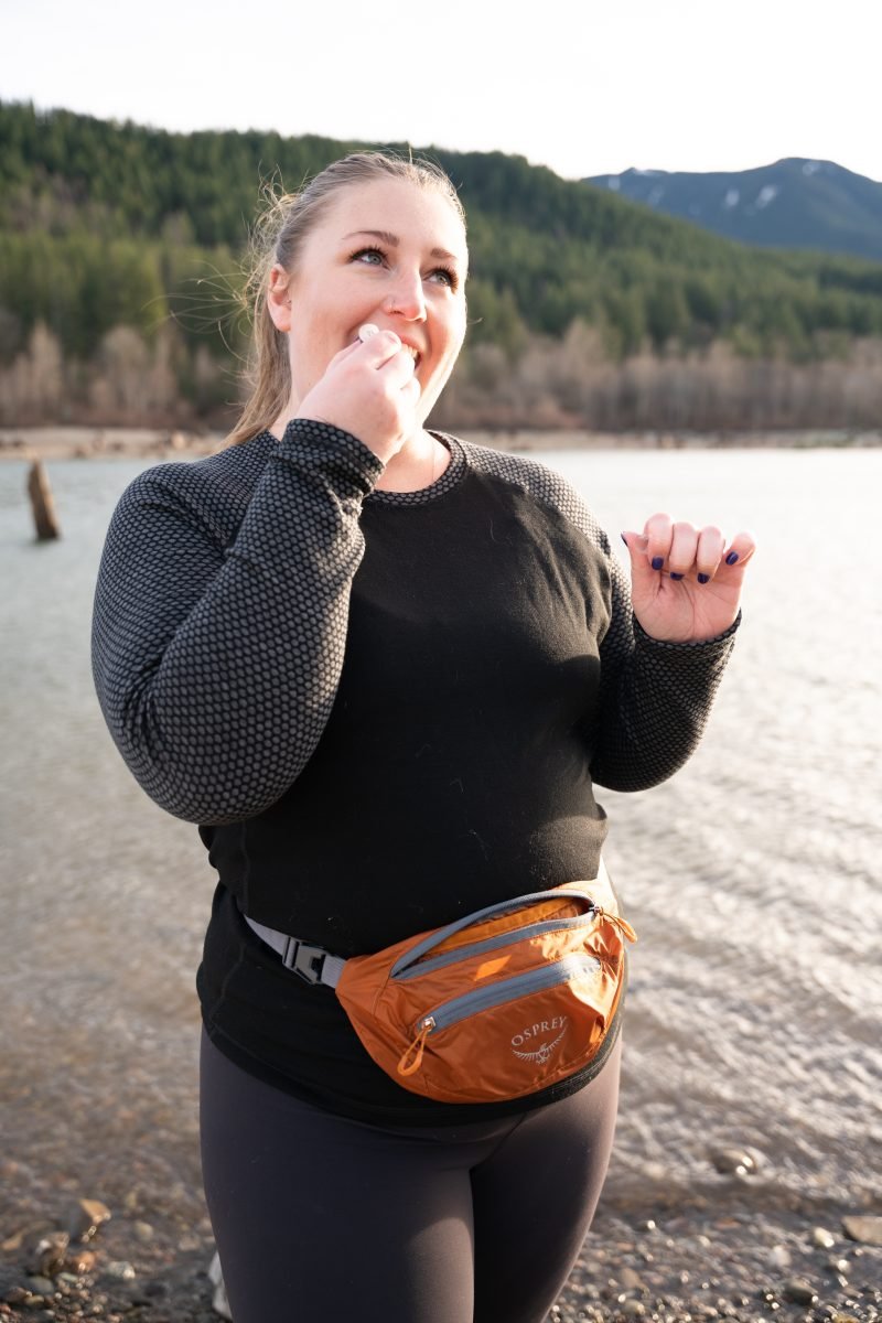 A woman wearing an orange waist pack applying chapstick