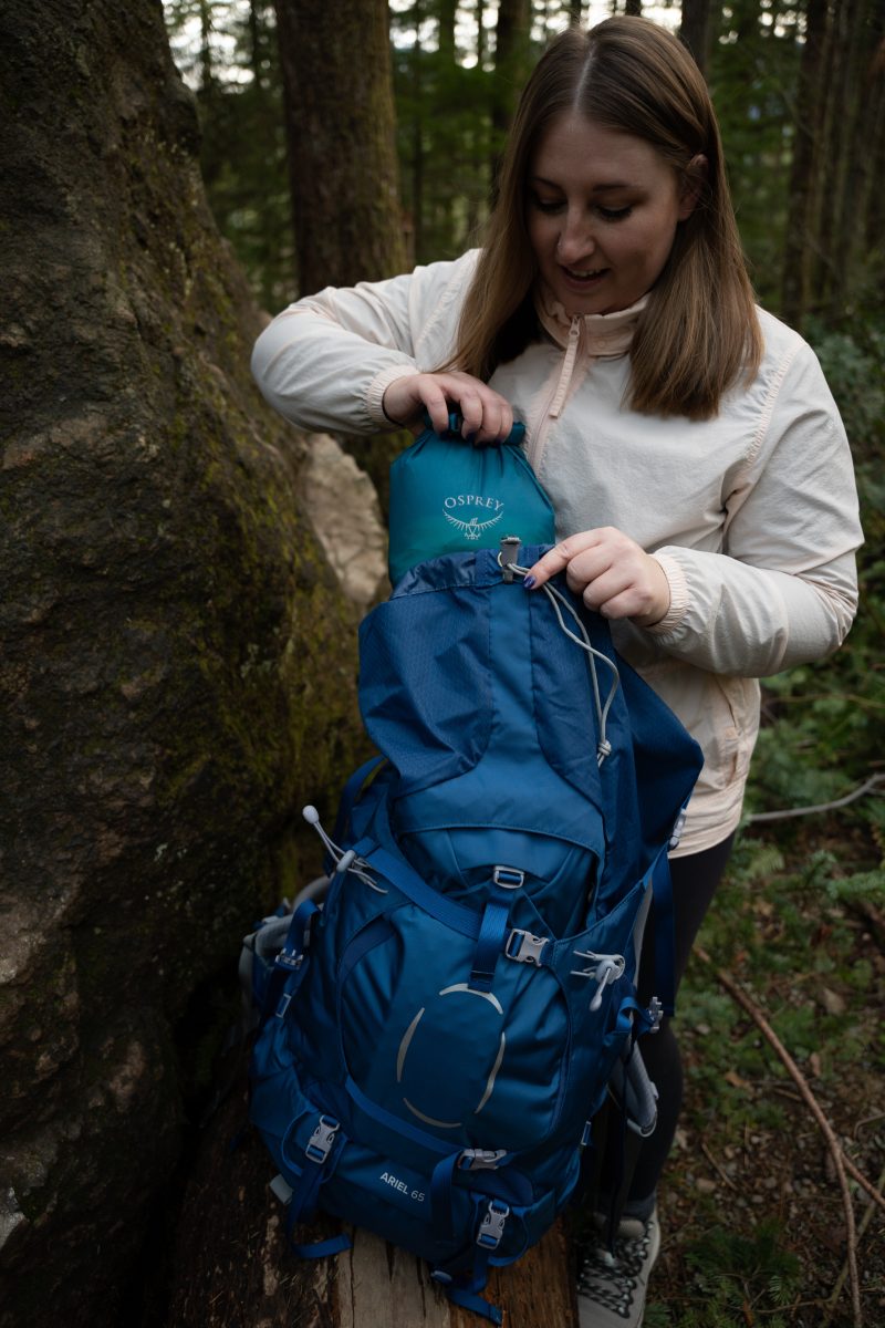 A woman adjusting her backpacking pack in the forest