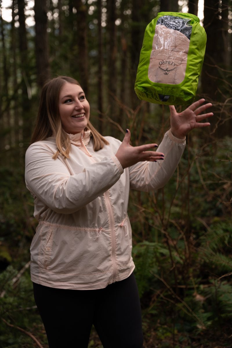 A woman tossing her stuff sack in the air, full of her items inside