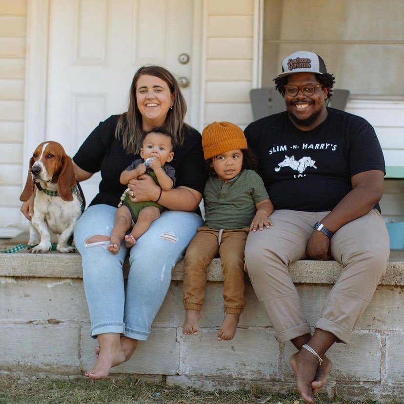 Two adults and two children sitting on a front porch with a dog
