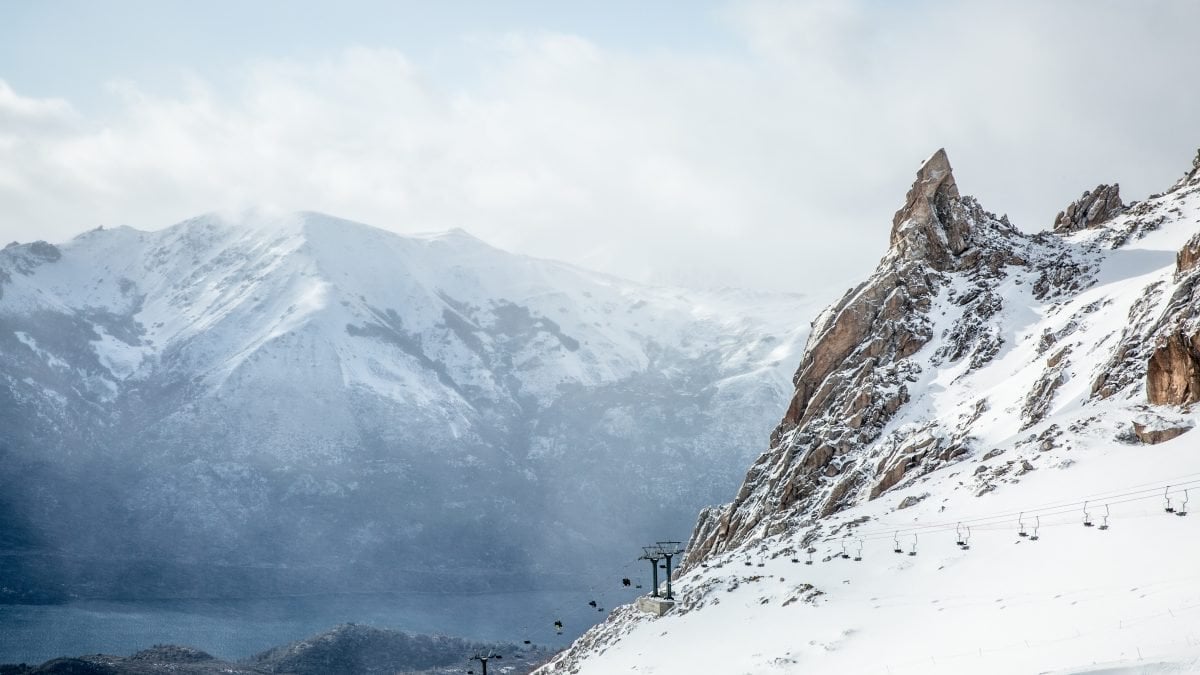 A landscape view of a ski lift, with snowy mountains in the background