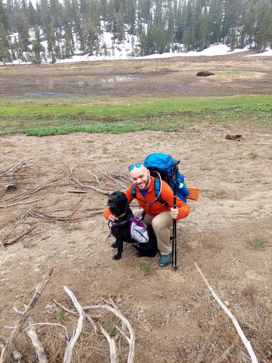 A man wearing backpacking gear with his black lab