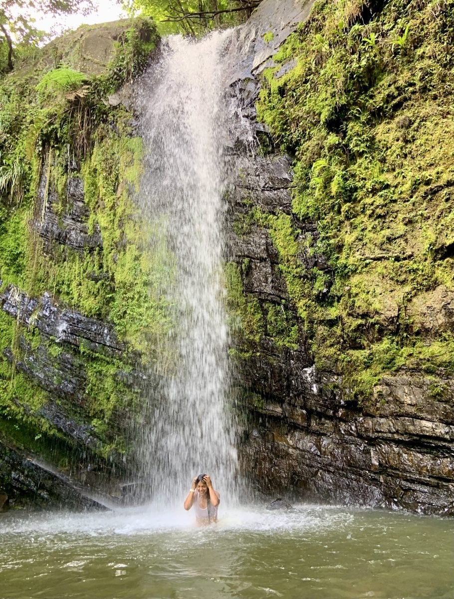 A woman standing under a waterfall