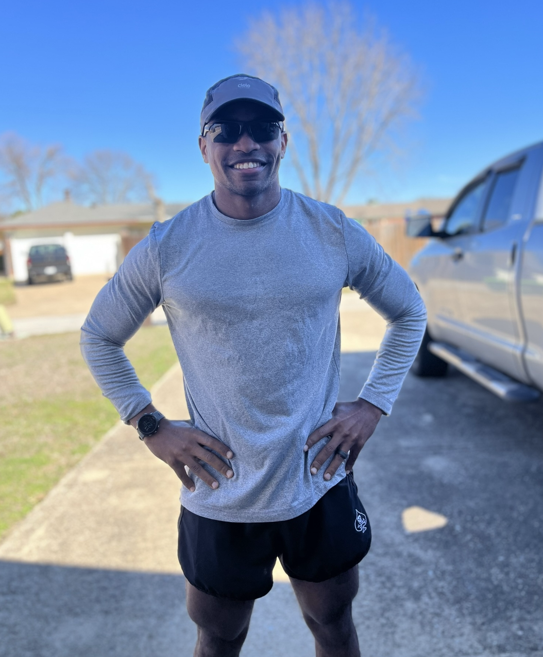 A man standing and smiling in a driveway wearing running gear