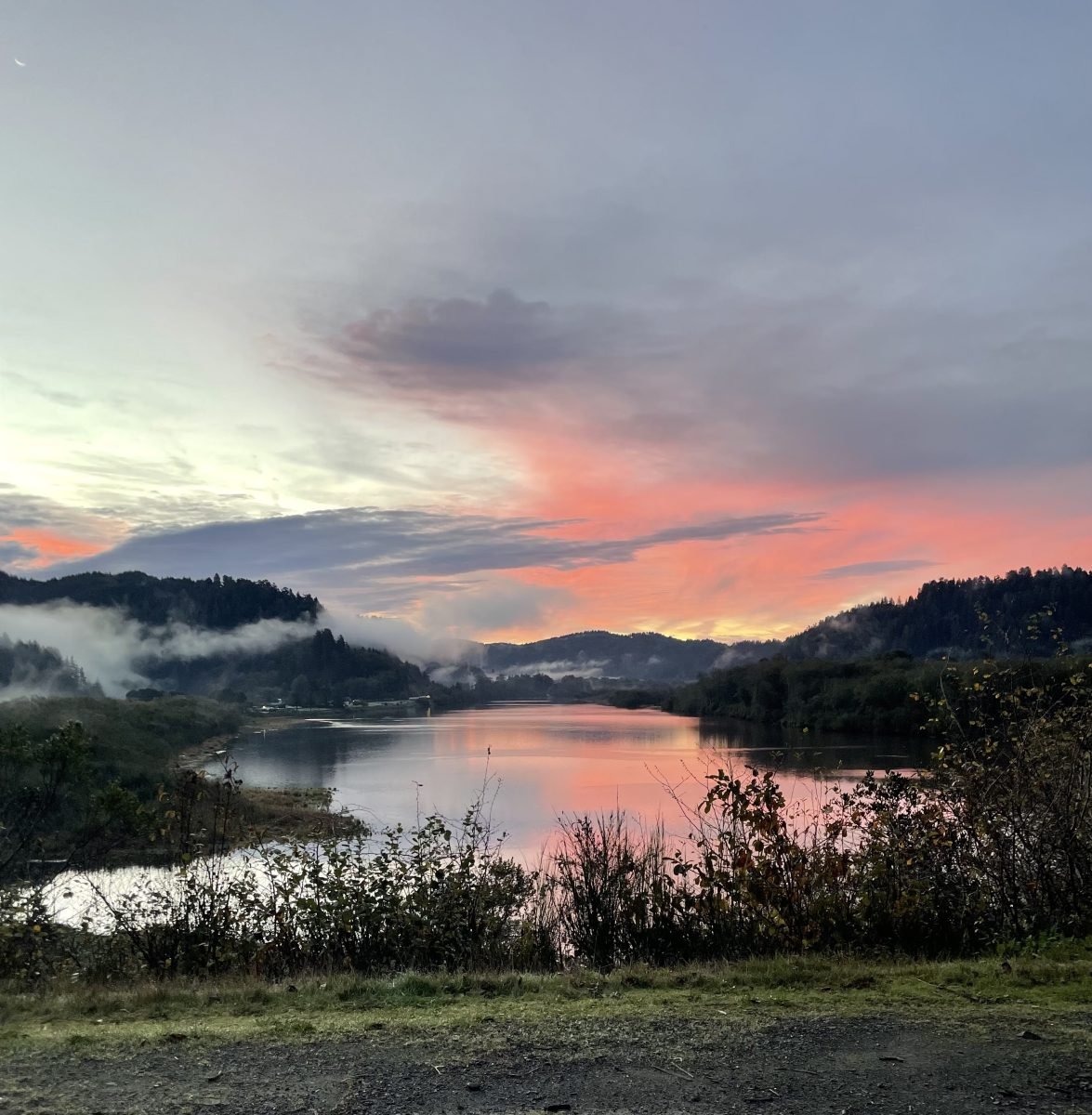 A sunset with a body of water in the foreground