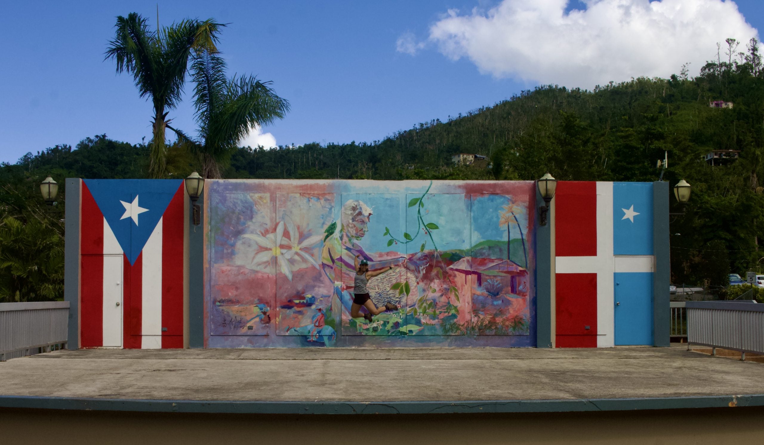 A woman jumping in front of a mural with flags on either side
