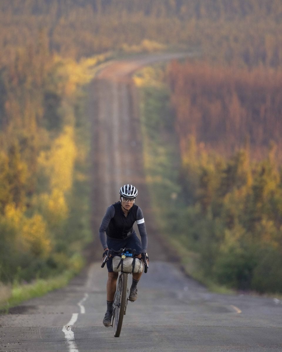 A person on a bike with colored trees in the background