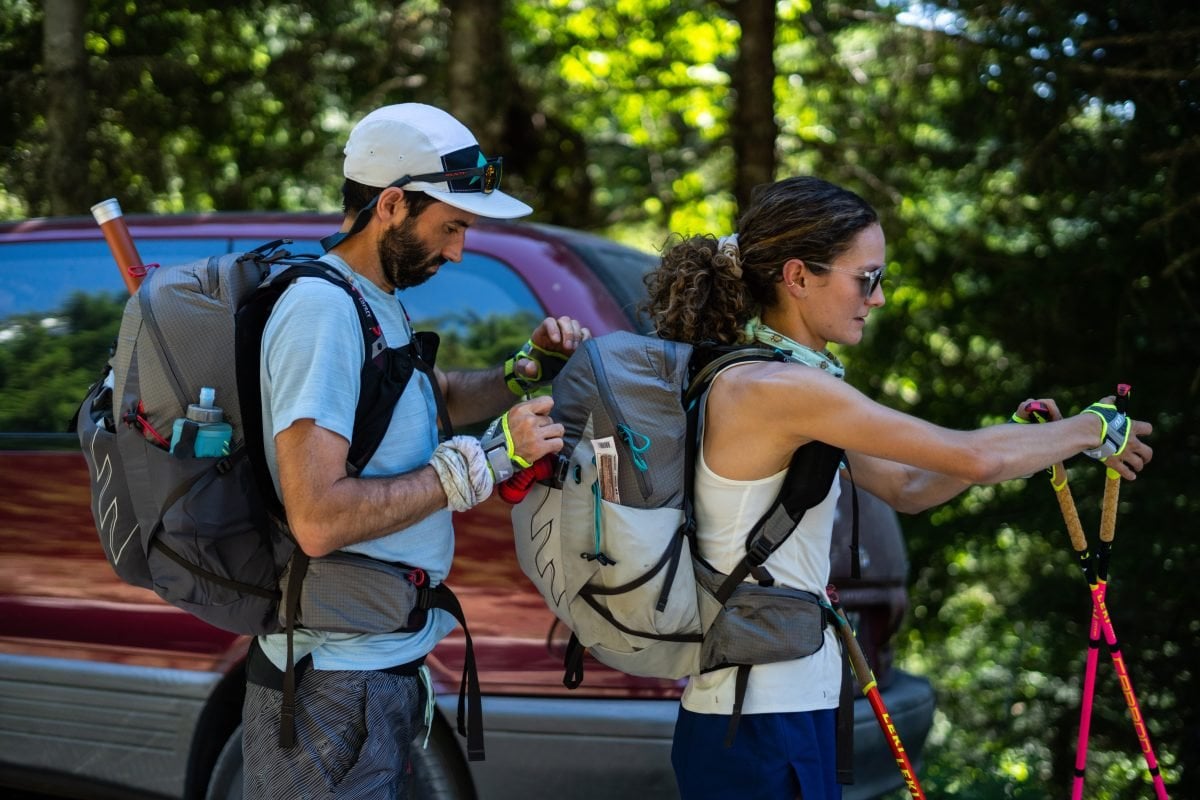 A man and woman loading up their packs before a run