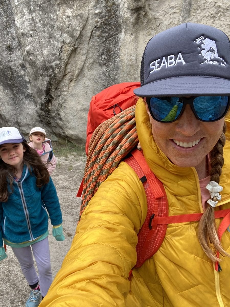 A woman wearing mountaineering gear with her two daughters behind her