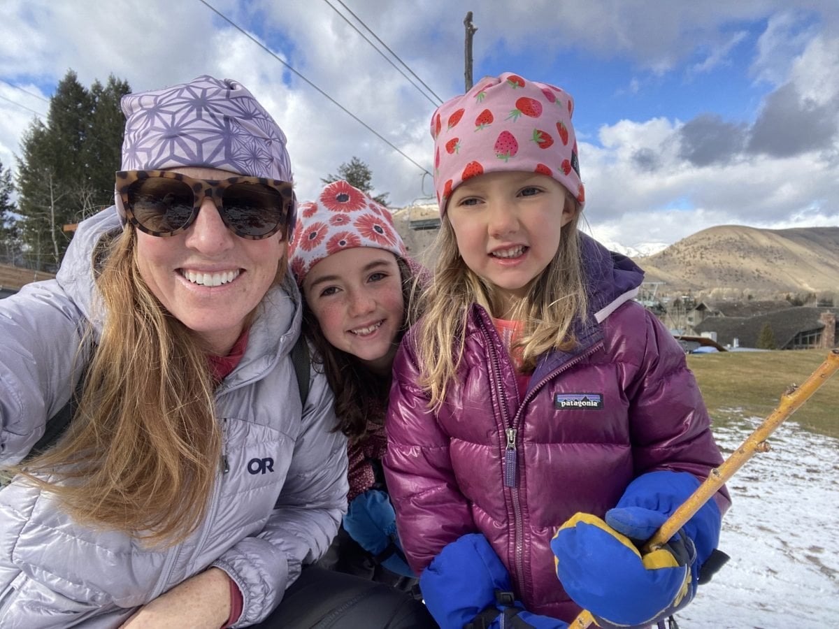 A woman outside with her two kids, all wearing coats and hats