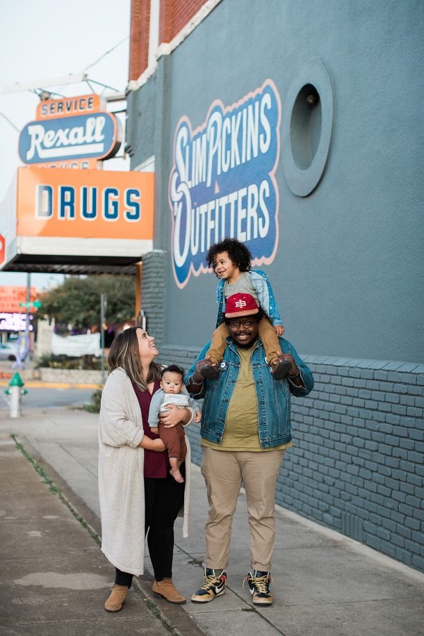A family of four standing outside of a building smiling and laughing with each other