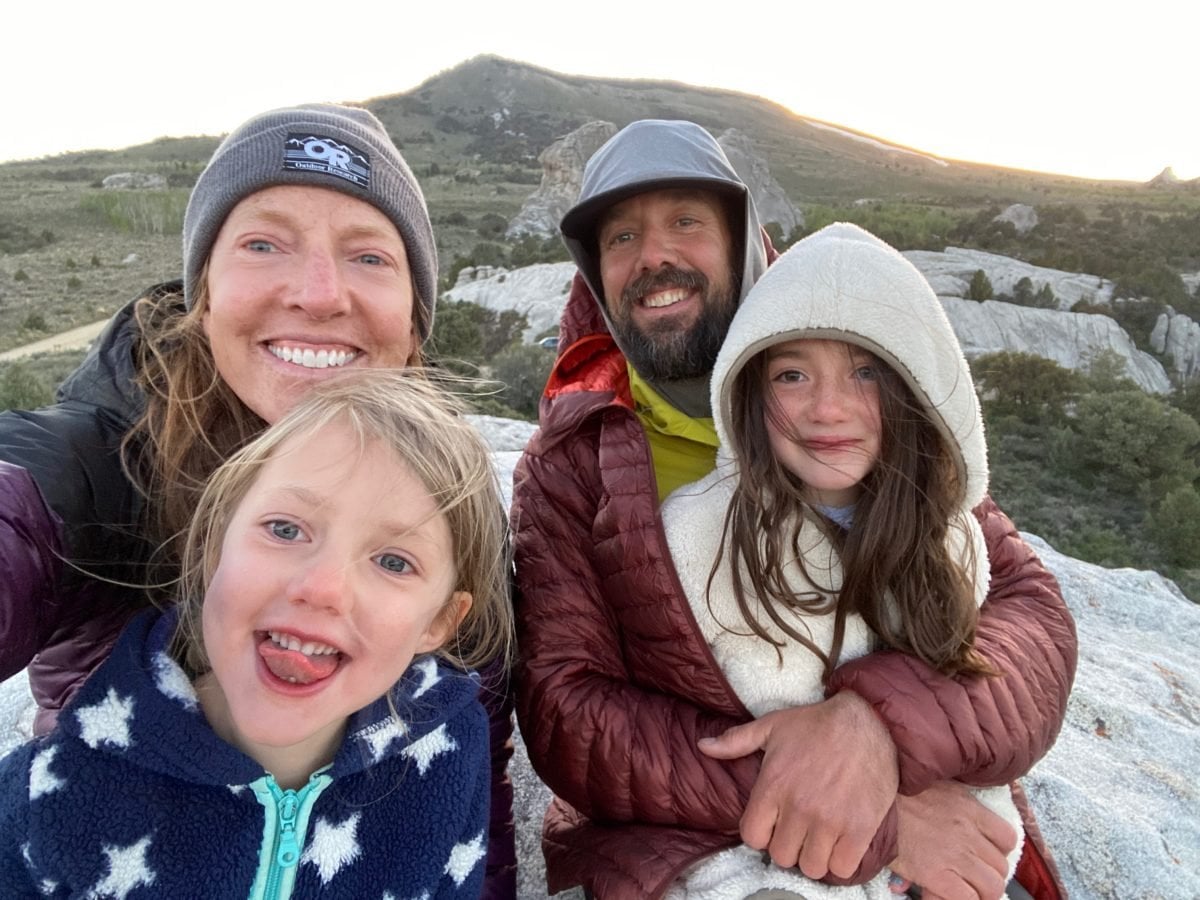 A woman and man with their two daughters on a rock outside