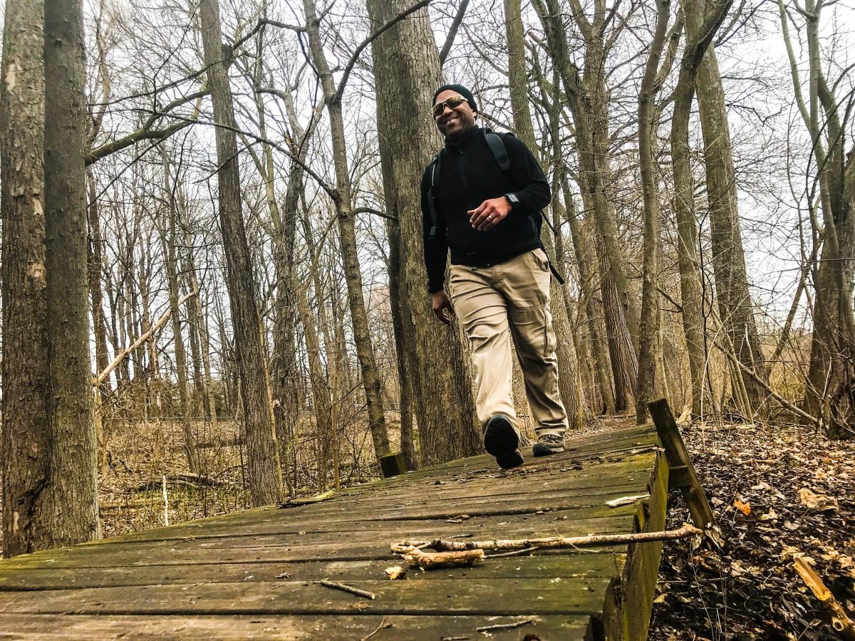 A man walking on a boardwalk through a forested trail