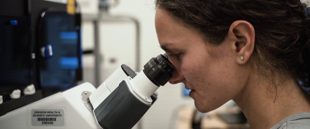 A woman looking into a microscope