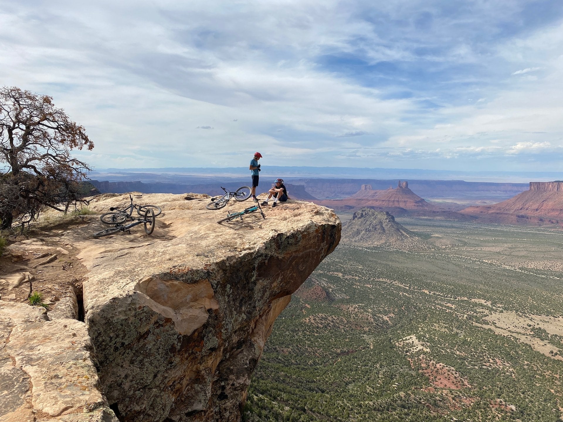A group of people resting on a rock ledge, with mountain bikes laying around them