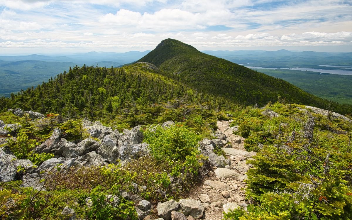 A landscape view of a trail atop a grassy mountain