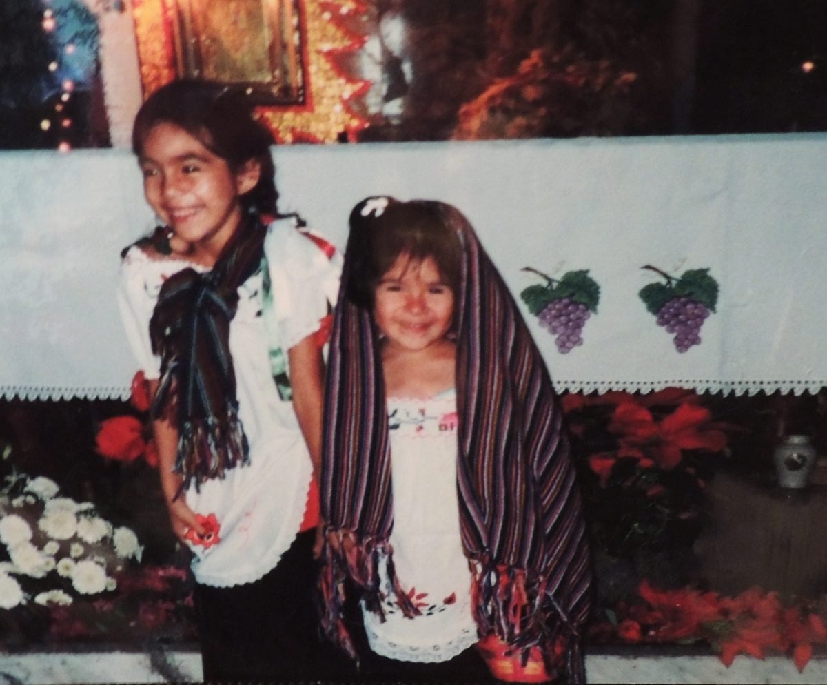 Two young girls wearing scarves and smiling