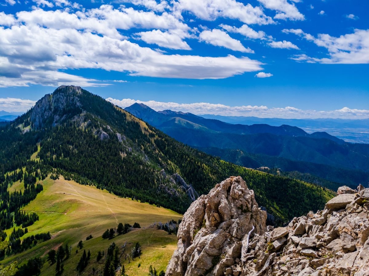 A landscape view of mountains with grass and trees surrounding the area