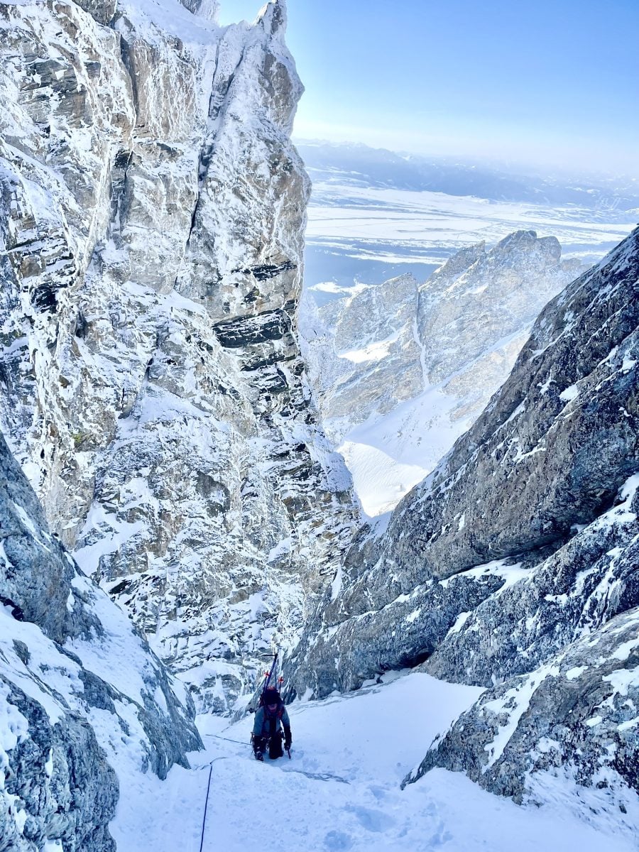 A skier climbing up a snow packed mountain, in full gear