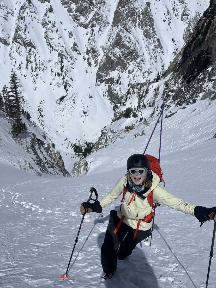 A woman in full ski gear touring up a snowy mountain