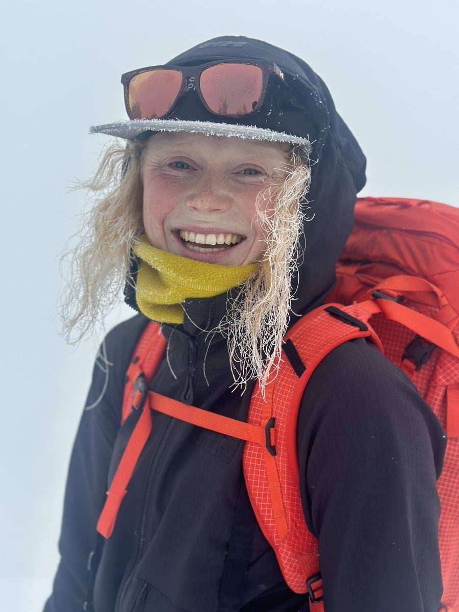 Osprey Athlete Madison Rose in a black jacket and orange Mutant pack smiling big and bright