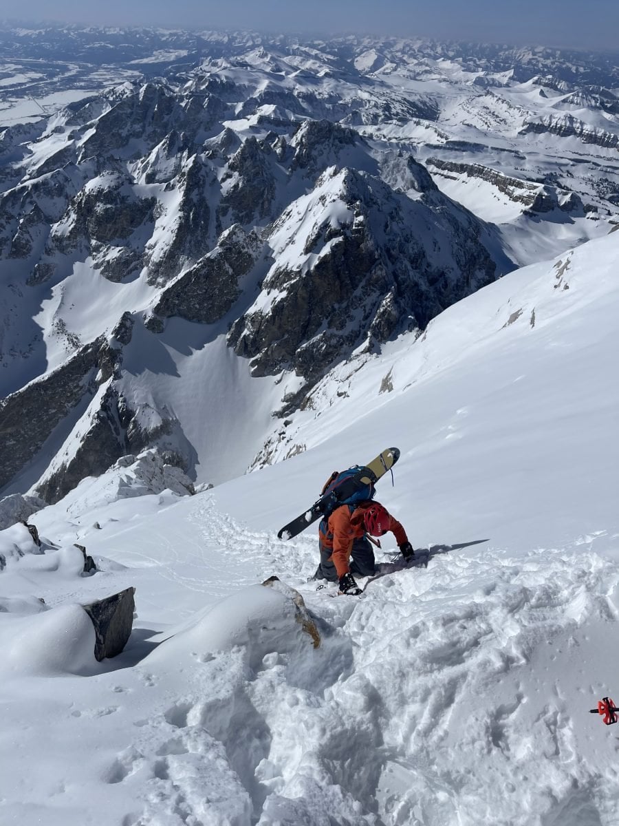 A skier climbing up a snow packed mountain, in full gear