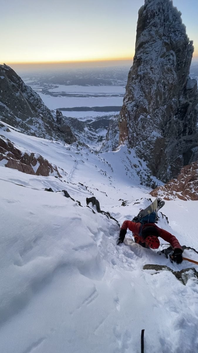 A skier climbing up a snow packed mountain, in full gear
