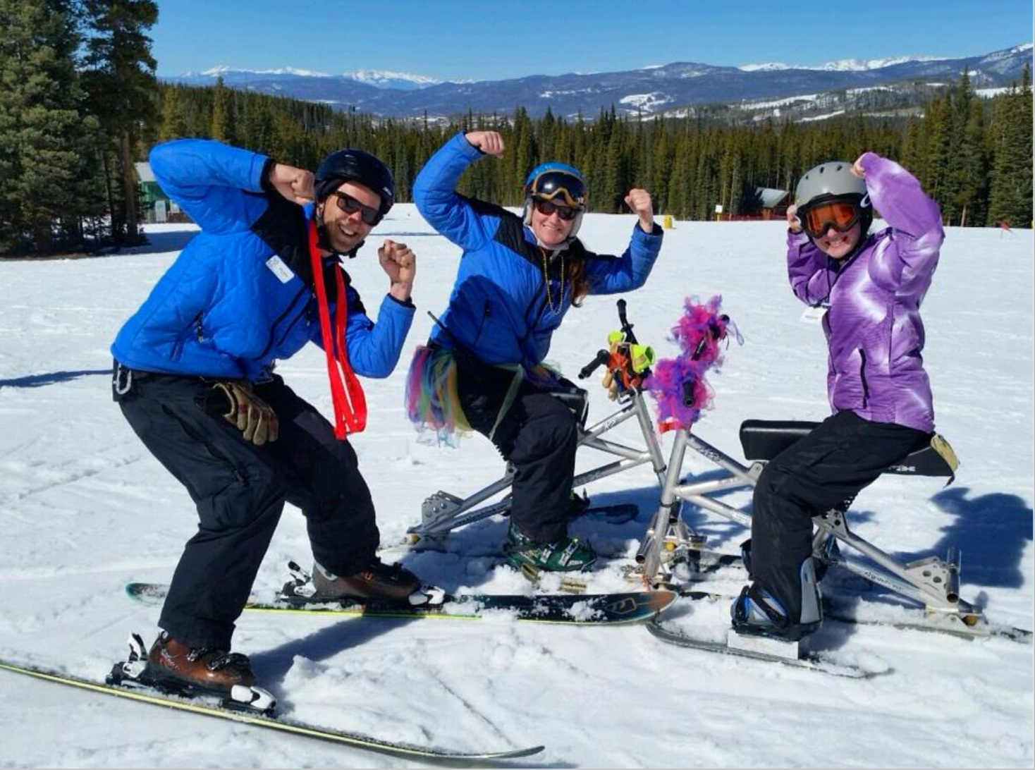Three people on a ski hill - two people on adaptive ski gear