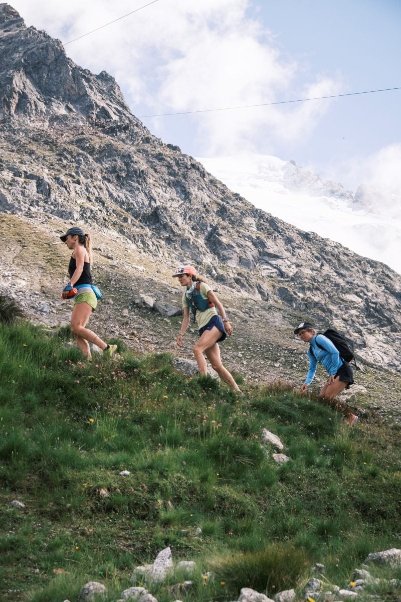 Three women on a trail, hiking up a hill on a trail run