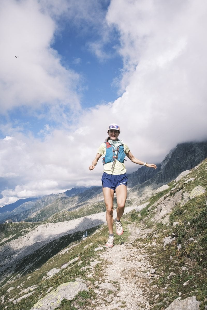 A woman running down a mountainous trail