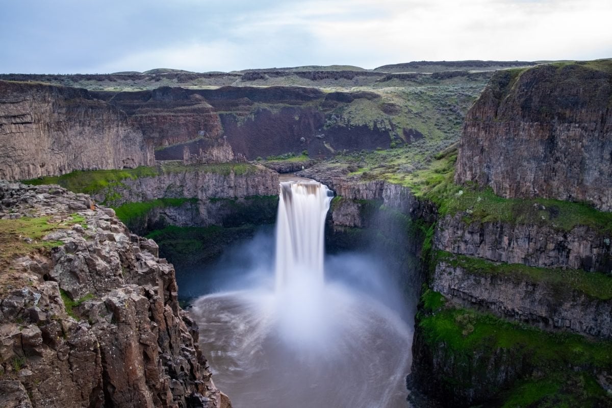 A waterfall cascading into a pool below, with rocks and cliff faces surrounding on all sides