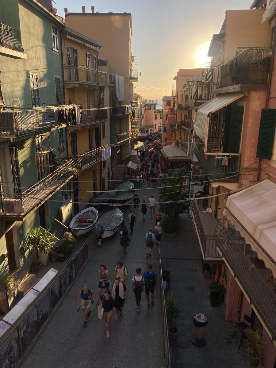 Looking down on a coastal town street, where people are walking in both directions